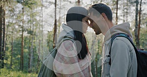 Side view of loving couple standing face to face enjoying closeness in beautiful forest on sunny day