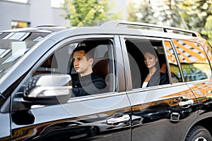 Side view of a luxury SUV vehicle with male driver and business lady