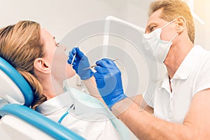 Side view on male dentist examining teeth of female patient