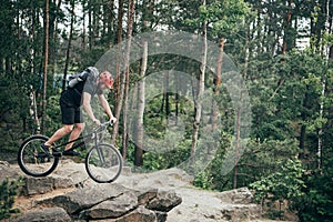 side view of male extreme cyclist in protective helmet doing stunt on mountain bicycle