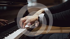 Side view of male hands playing a concert piano