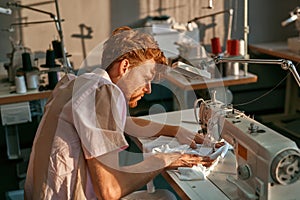 Side view of male tailor working on sewing machine