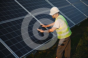 Side view of male worker installing solar modules and support structures of photovoltaic solar array.