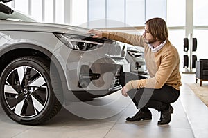 Side view of man buyer, client in casual clothes choosing auto.