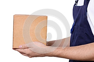 Side view of man in dark blue overalls giving cardboard box, isolated on white background