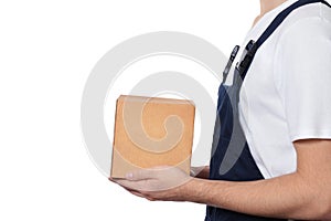 Side view of man in dark blue overalls holding cardboard box, isolated on white background