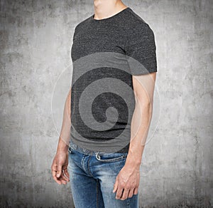 Side view of a man in a dark grey t-shirt and denims.