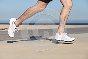 Side view of a man legs running on the concrete of a seafront