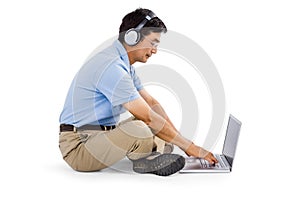 Side view of man listening music while using laptop