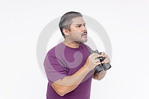 Side view of a man looking confused upon seeing something mysterious with his binoculars. Speechless and dumbstruck expression.