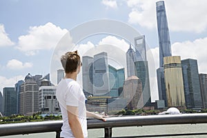 Side view of man looking at Shanghai World Financial Center against cloudy sky photo