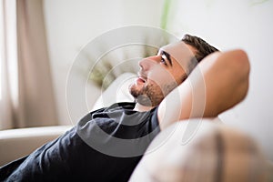 Side view Man lying and relaxing on the couch at home in the living room