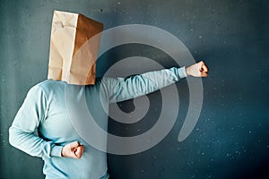 Side view of man with a paper bag on head with clenched fists in fighting stance, practicing karate punching