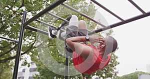 Side view man with prosthetic leg doing abs suspended in the air