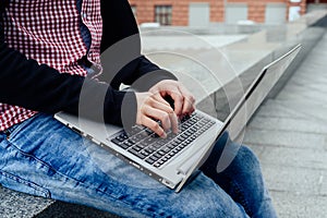 Side view of man`s hands typing on laptop computer outdoors