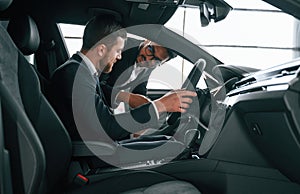 Side view. Man showing automobile interior to the customer