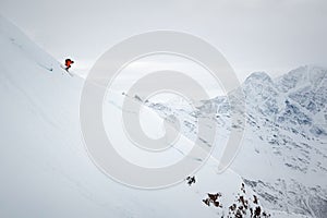 Side view of a man on skis in colorful clothes jumping from a mountain snowy slope against the backdrop of epic high