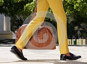 Side view of man walking outdoors on city street with bag