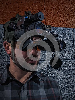 Side view of a man wearing a professional night vision binocular system created by dual monoculars on a bridge mount