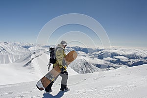 Side view manful snowboarder walking with the snowboard in the m photo