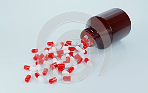 Side view of many capsule pills red and white capsule came out from a brown glass bottle. Realistic medical drug.