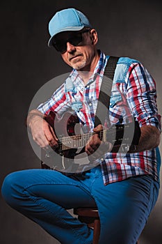 Side view of a mature man playing an electric guitar