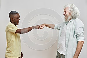 Side view of mature multiracial men bumping fists