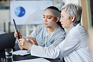 Side view of mature radiologist explaining results of x-ray to her assistant