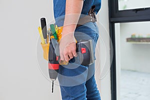 Side view mid section of a handyman with drill and toolbelt