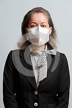 Side view of middle aged mixed race woman in formal wear wearing white surgical mask for protection against coronavirus COVID-19