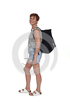 Side view of a middle aged woman on a summer day with backpack lookig at camera