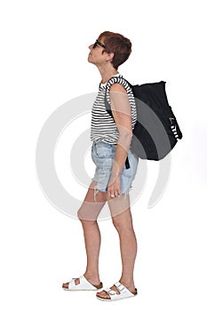 Side view of a middle aged woman on a summer day with backpack lookig up with sunglasses