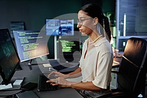 Focused Female IT Programmer with Glasses Using Computer Writing Code in Office