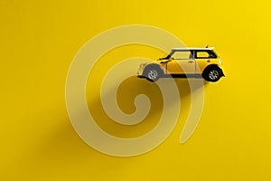 Side view of a Mini Cooper S Yellow toy car on a yellow background with a long shadow