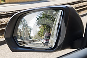 Side view mirror in modern car with view of street with parked c