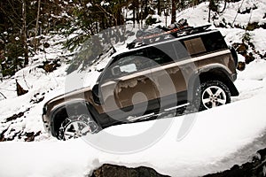 side view of modern off-road car ride on snowy road at mountains. Mountain tourism transport.