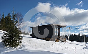 Side View of a modern tiny cabin on top of snowy mountain in Ukraine