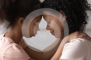 Side view mother and daughter touches foreheads moment of tenderness