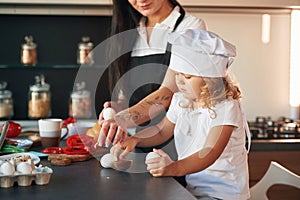 Side view. Mother with her daughter are preparing food on the kitchen