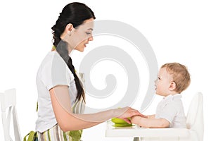 side view of mother holding hands of baby boy in highchair