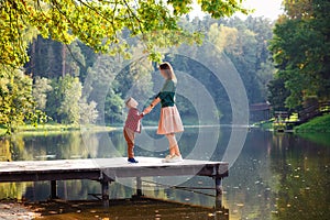 Side view of a mother and a young son standing together on a wooden bridge on a lake in the summer. Family, summer, vacation, love