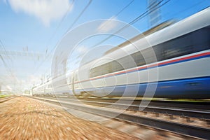 Side view of the moving ultra high speed train runs on rail way with railway infrustructure in the blurred background with flare e