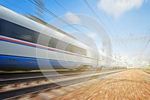 Side view of the moving ultra high speed train runs on rail way with railway infrastructure in the blurred background with flare e