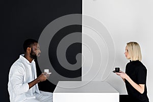 side view of multicultural couple sitting with cups