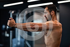 Side View Of Muscular Shirtless Black Man Training With Kettlebell At Gym
