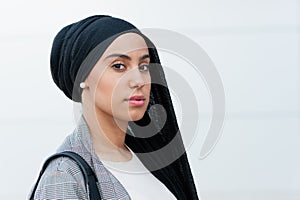 Side view of a muslim adult woman looking at camera in the park