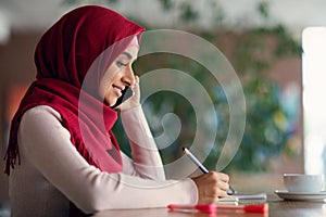 Side view of muslim woman talking on cellphone at cafe