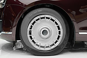 Side view on new luxury car wheel on silver metal rim with black shine tire. Modern classic car wheel