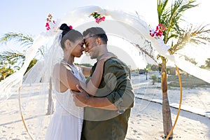Side view of newlywed caucasian couple with face to face standing at beach at wedding ceremony