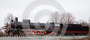 Side view of old classic black steam locomotive with red decoration